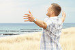 Mann am Meer breitet Arme aus