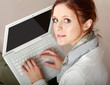 Photo: A young woman with a laptop sitting isolated on grey background A young woman with a laptop sitting isolated on grey background