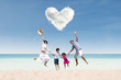 Happy family jumping under love cloud at beach