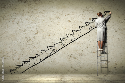 Photo: Woman standing on ladder drawing on wall Woman standing on ladder drawing on wall