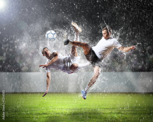 Photo: two football players striking the ball two football players striking the ball