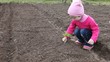 The little girl put the plant into the ground.