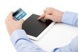 Man's hand holding a credit card over a tablet computer and the