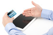Man's hand holding a credit card over a tablet computer and the