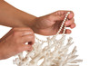 a pearl necklace in her hands against the backdrop of coral
