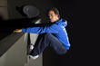 free runner scaling or climbing a wall at night to do parkour
