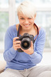 Female photographer with DSLR at home sitting on the floor