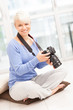 Female photographer with DSLR at home sitting on the floor