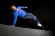 free runner doing parkour at night on a rooftop