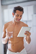 Man Wrapped in Towel holding a glass of water  and tablet