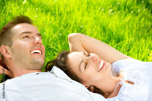 Photo: Young Couple Lying on Grass Outdoor Young Couple Lying on Grass Outdoor