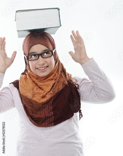 Photo: Female Arabic student balancing big book on head Female Arabic student balancing big book on head