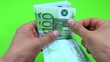 person counting euro in green background