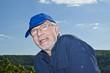 charismatic man in his 70s posing in front of blue sky
