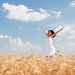 Happy woman jumping in golden wheat