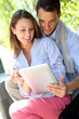 Couple websurfing on internet with tablet in park