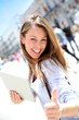 Cheerful girl with tablet showing thumb up