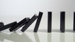row of dominoes with one falling over on white background