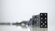 row of dominoes with one falling over on white background