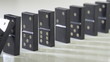 row of dominoes with one falling over on white background