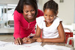 Mother Helping Daughter With Homework In Kitchen