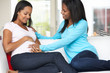 Photo: Woman Visiting Pregnant Friend At Home Woman Visiting Pregnant Friend At Home