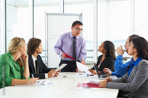 Photo: Businessman Conducting Meeting In Boardroom Businessman Conducting Meeting In Boardroom