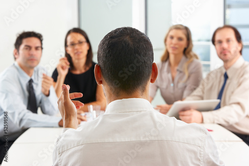 Photo: View From Behind As CEO Addresses Meeting In Boardroom View From Behind As CEO Addresses Meeting In Boardroom