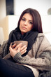 Young pensive woman in cozy warm clothings with cup of coffee