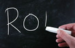 The word "ROI" handwritten with white chalk on a blackboard