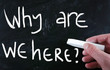 "why are we here" handwritten with white chalk on a blackboard