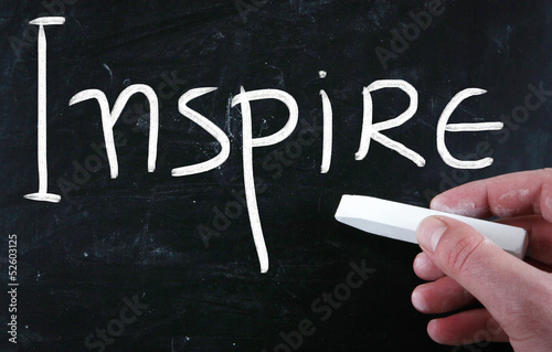 Photo: "Inspire" handwritten with white chalk on a blackboard "Inspire" handwritten with white chalk on a blackboard