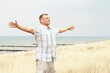 Mann am Meer breitet Arme aus