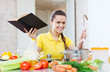 happy woman cooking  vegetables with book