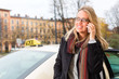 Junge Frau steht vor einem Taxi und telefoniert