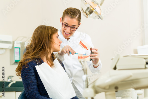 Photo: Zahnärztin mit Zahnbürste, Gebiss und Patientin Zahnärztin mit Zahnbürste, Gebiss und Patientin