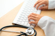 Doctor typing on keyboard with stethoscope