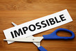 Word impossible cut to possible over wood background