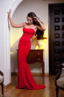 Attractive girl in a long red dress posing in a vintage scene