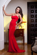 Attractive girl in a long red dress posing in a vintage scene