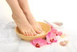 Female feet in spa bowl with sea salt, isolated on white