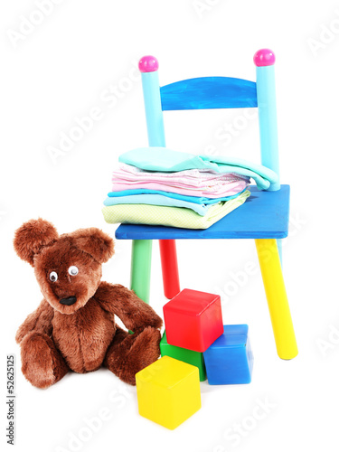 Photo: Small and colorful chair with baby clothes isolated on white Small and colorful chair with baby clothes isolated on white