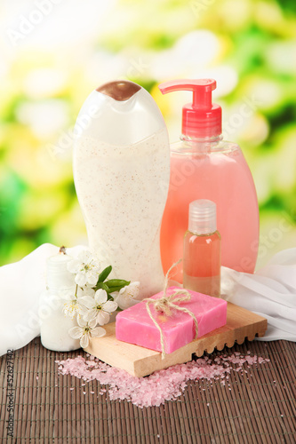Photo: Cosmetics bottles and natural handmade soap on green background Cosmetics bottles and natural handmade soap on green background
