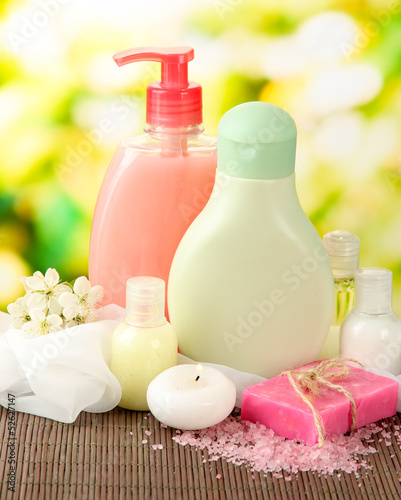Photo: Cosmetics bottles and natural handmade soap on green background Cosmetics bottles and natural handmade soap on green background