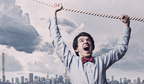 Leinwandbild Motiv Businessman hanging on rope