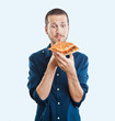 portrait of a young beautiful man eating a slice of pizza marghe