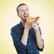 portrait of a young beautiful man eating a slice of pizza marghe