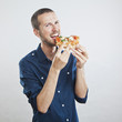 portrait of a young beautiful man eating a slice of pizza marghe