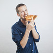 portrait of a young beautiful man eating a slice of pizza marghe