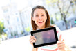 Cheerful girl in town showing tablet screen